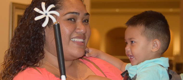 A blind mom smiles while holding her son.