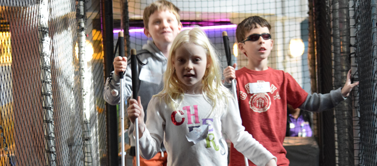 Three blind kids find their way through a maze with their long white canes.